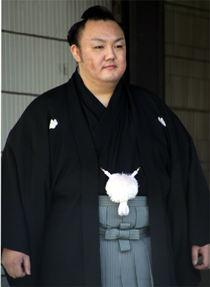 黒い紋付袴姿で髷を結った力士（土俵の目撃者の撮影写真）